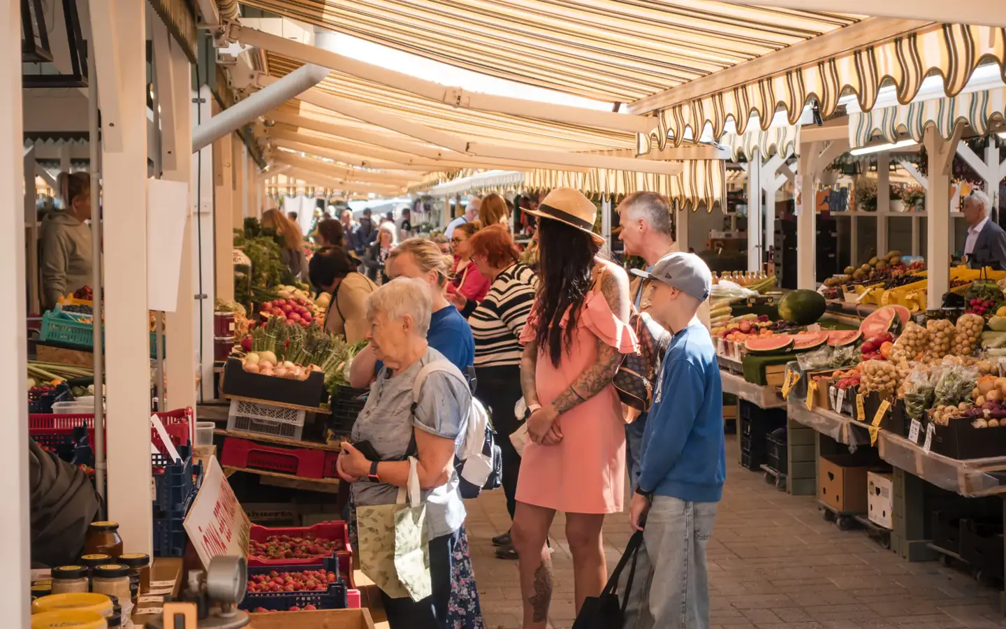 Shoppers comparing produce at a busy covered farmers market