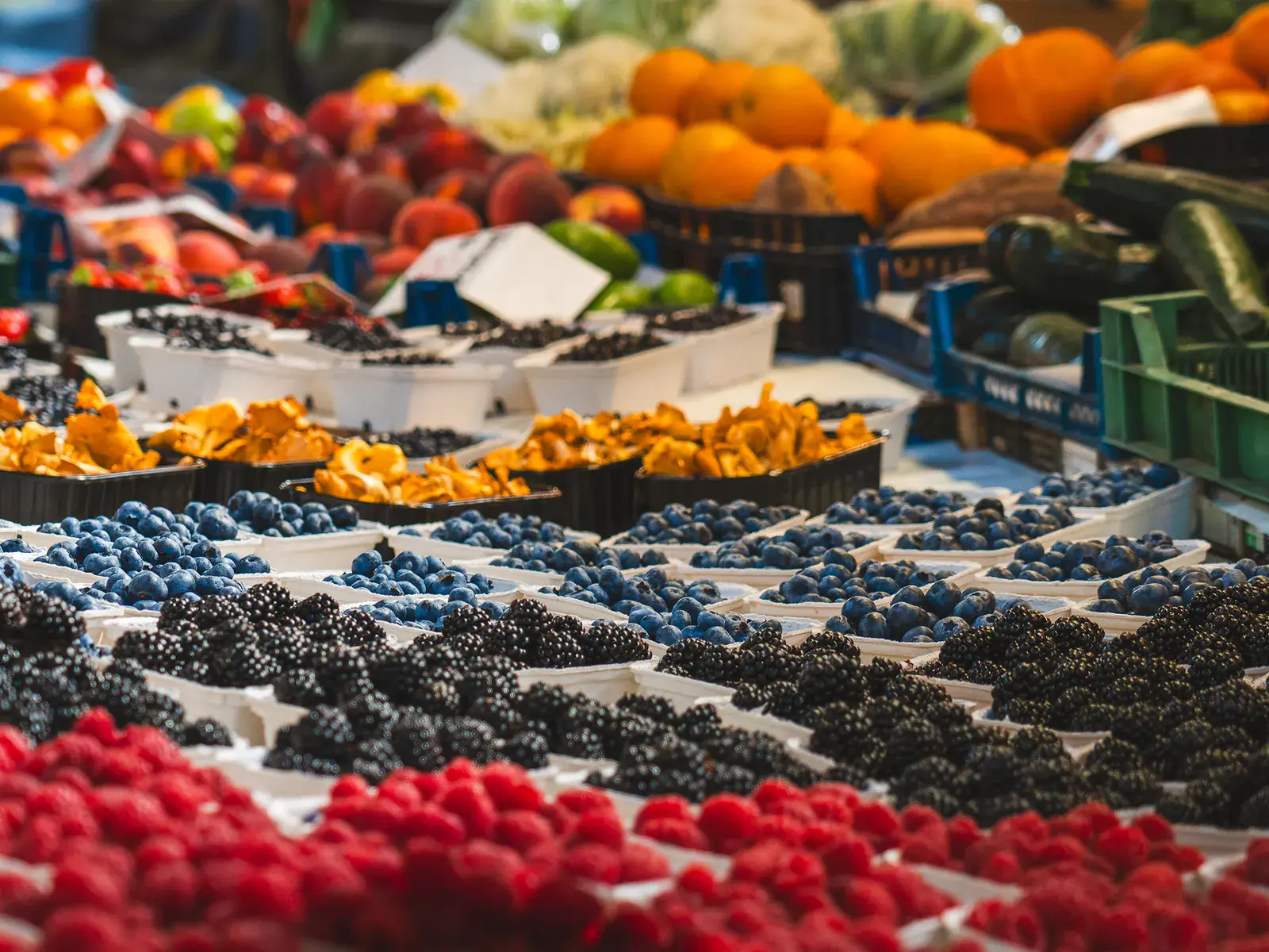 A market stall filled with colorful berries and vegetables