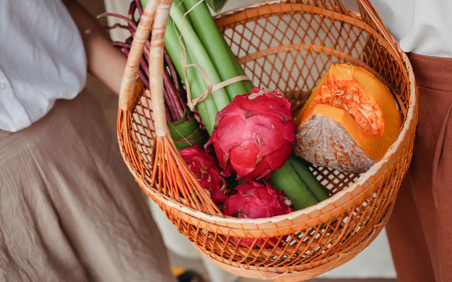 A shopper holding a woven basket filled with colorful produce