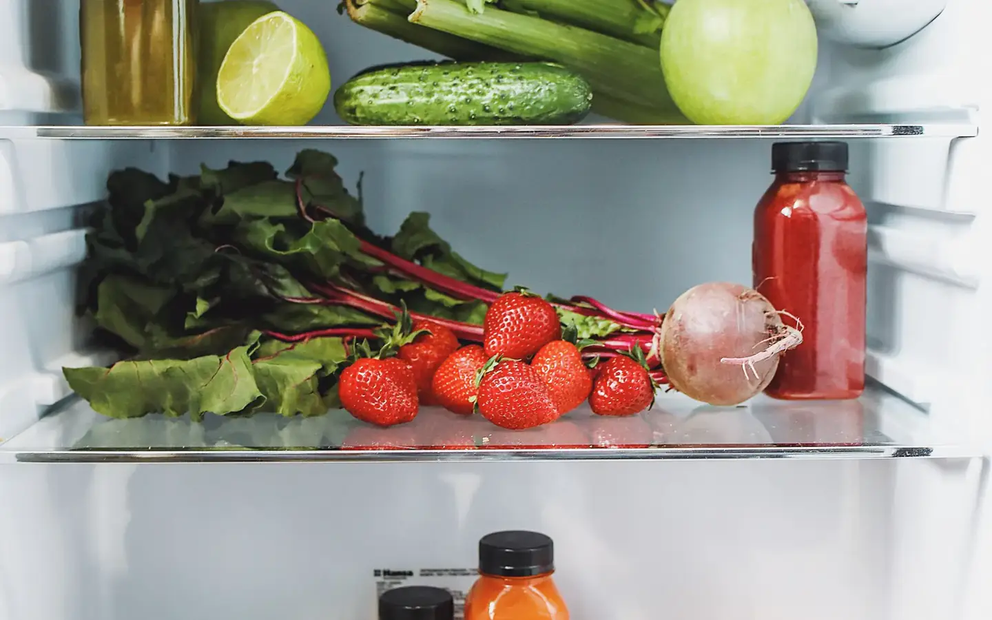 Fresh vegetables and strawberries arranged on refrigerator shelves