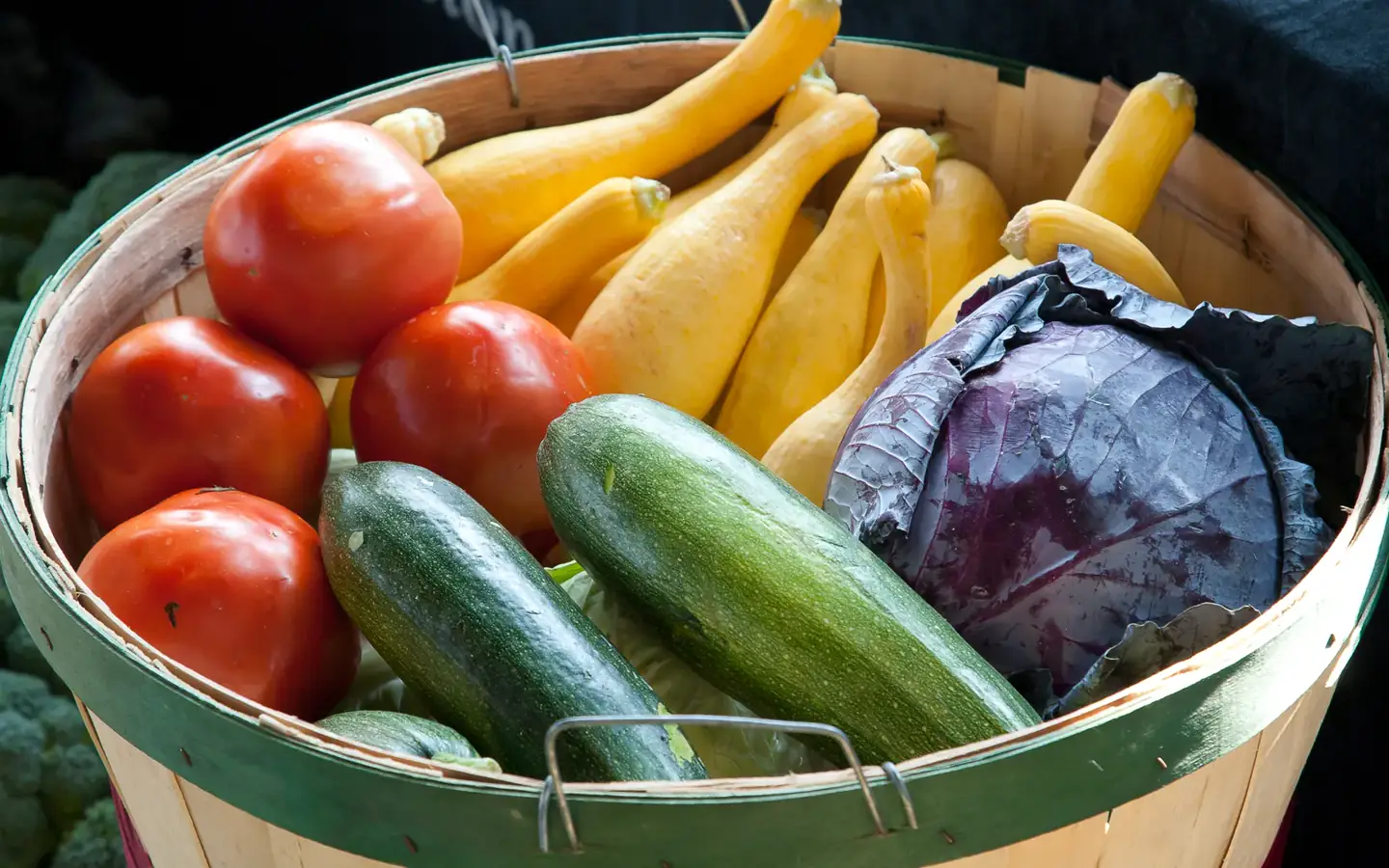 Tomatoes, squash, zucchini, and cabbage in a wooden harvest basket