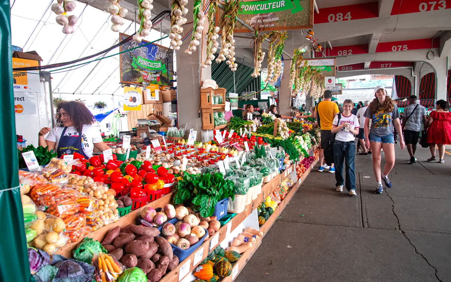A colorful produce stall with shoppers walking through the market